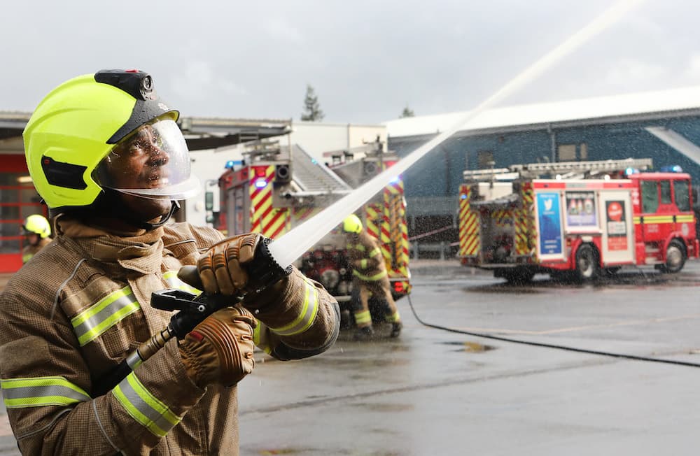Trainee Firefighter holding a hose spraying water