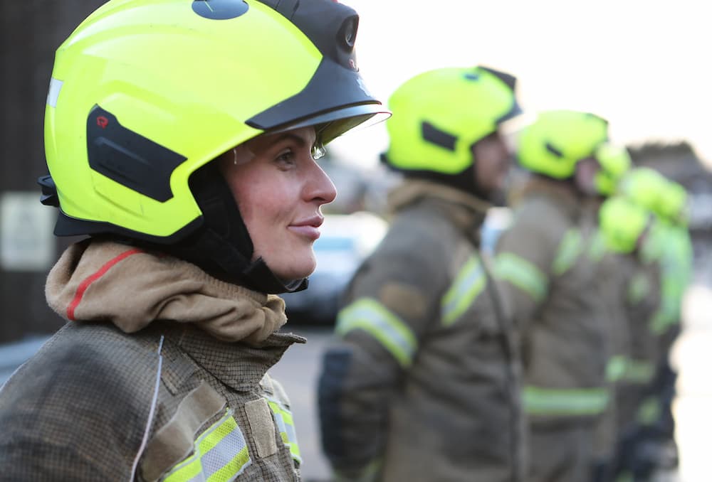 Trainee Firefighters stood in a line with a female firefighter in focus