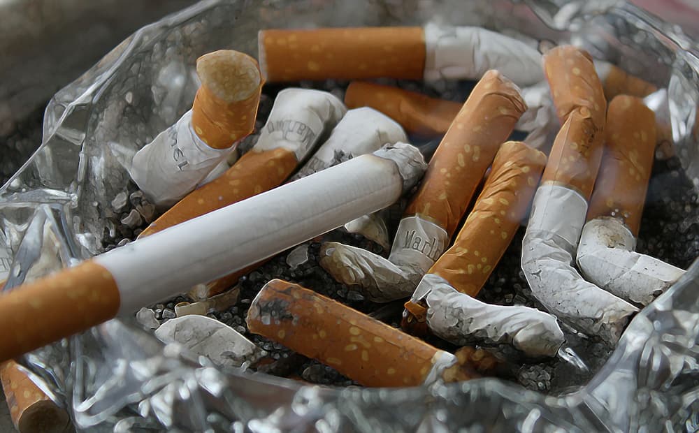Several cigarettes in an ash tray with one still lit