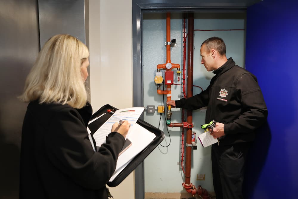 Two fire safety officers inspecting pipework at a property