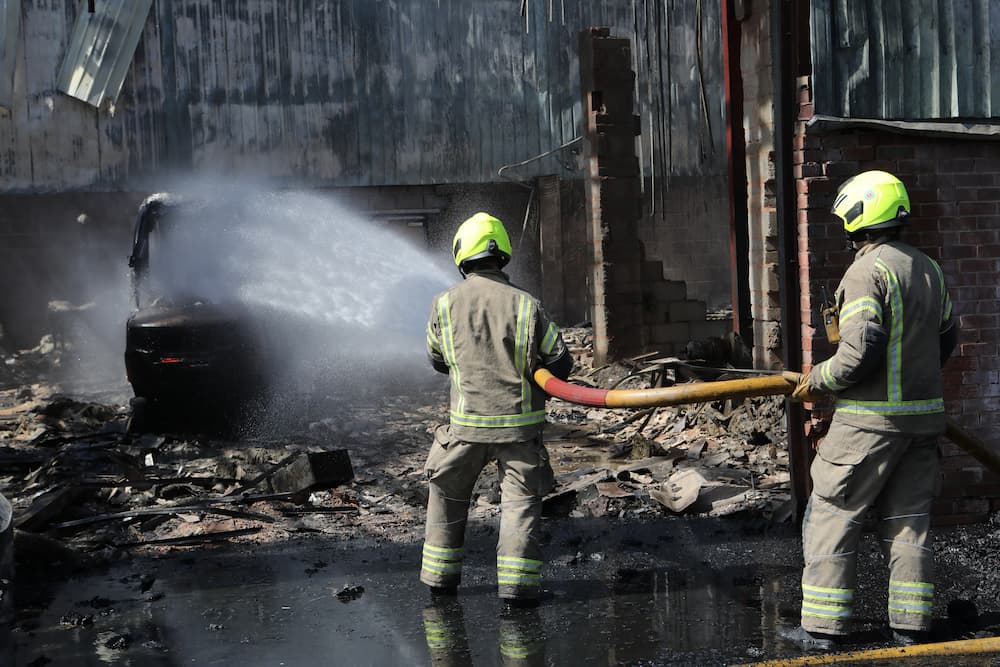 Firefighters using a hose reel to spray water on a fork lift truck