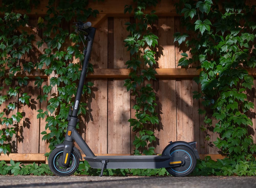 A black e-scooter parked next to a fence