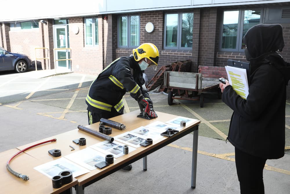 A firefighter candidate assembling some equipment on a table while being assessed