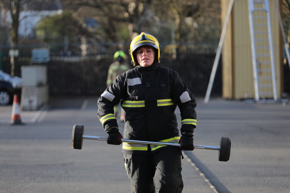 A firefighter candidate carrying bar bells