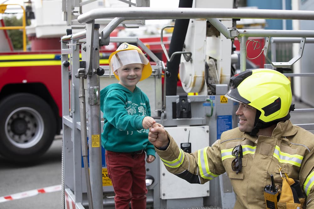 A firefighter and young boy bumping fists at a station open day