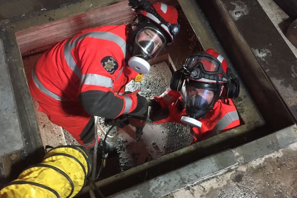 Two technical rescue staff in a confined space weather breathing masks