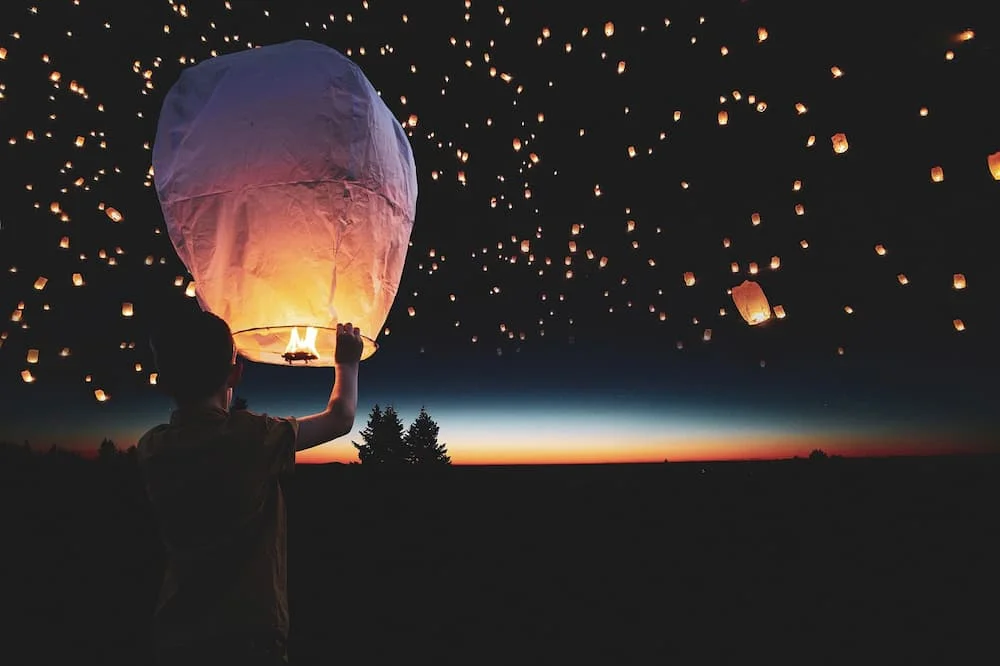 A man releasing a sky lantern into the night sky