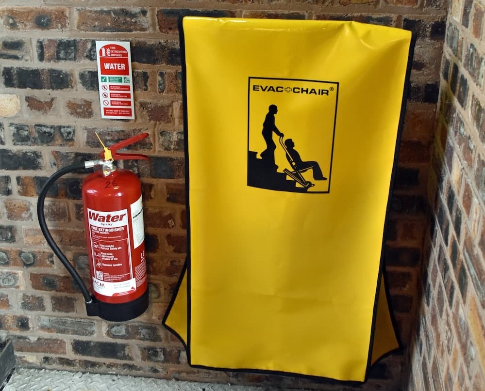 An evacuation chair in a stairwell next to a fire extinguisher