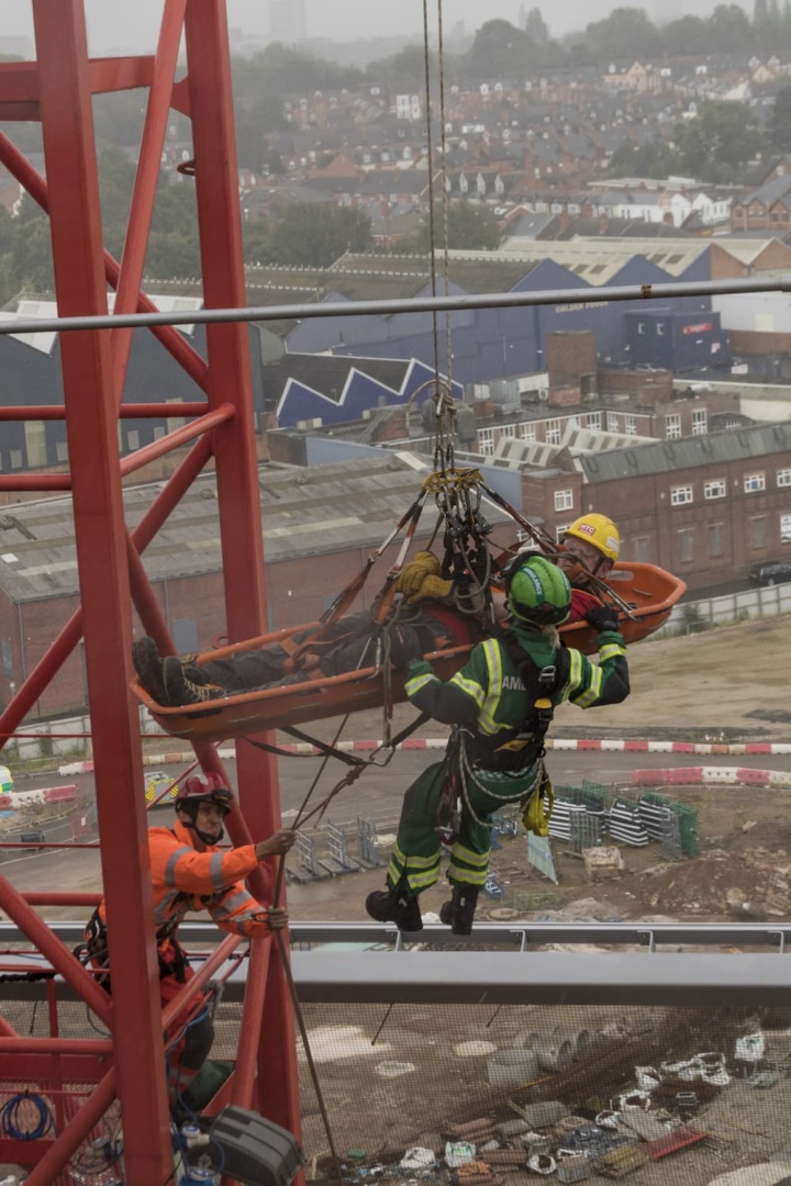 A firefighter suspended on a harness assisting a stretcher in mid-air