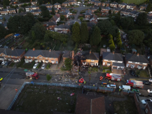 An aerial shot from a drone of a destroyed house with fire service outside