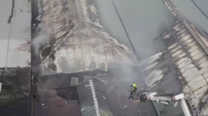 Aerial shot showing firefighter on a hydraulic platform checking roof