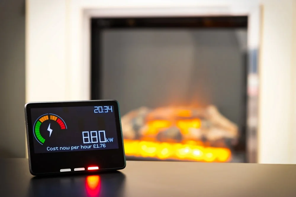 A smart meter home monitor with a fire in the background