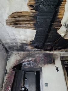 A photo inside a property showing fire damage to door frame and ceiling