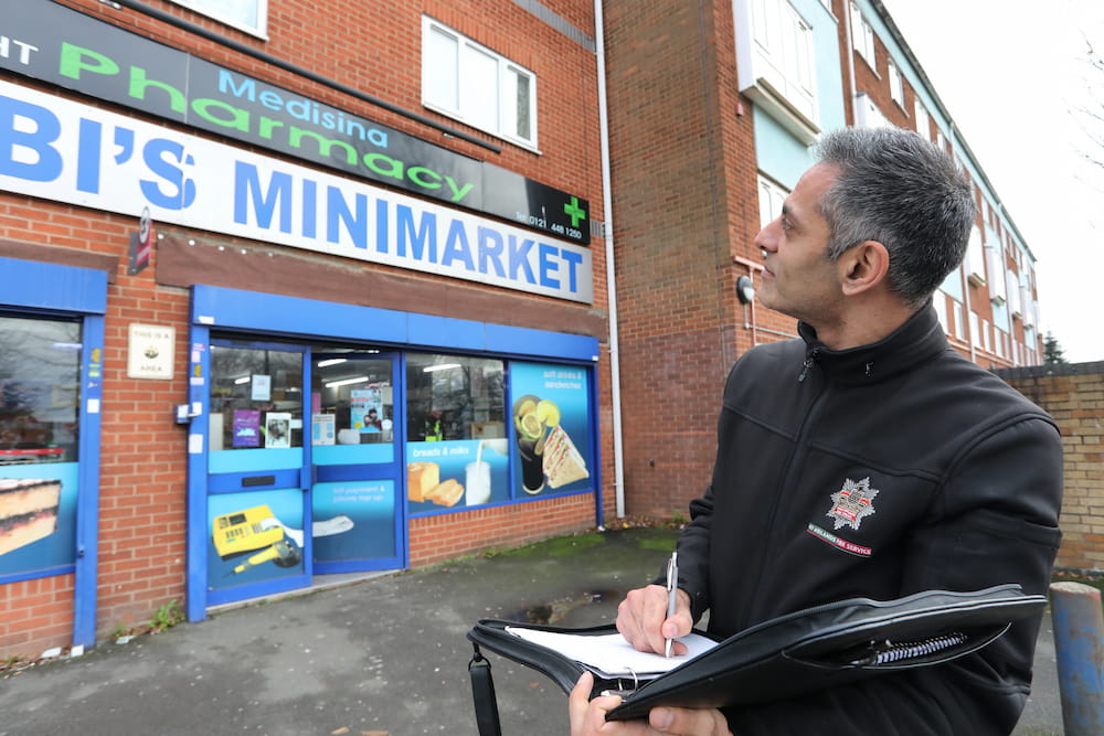 A fire safety officer with a notebook assessing the outside of a small business