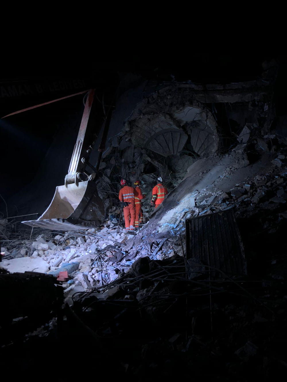 UKISAR personnel working in rubble next to excavator