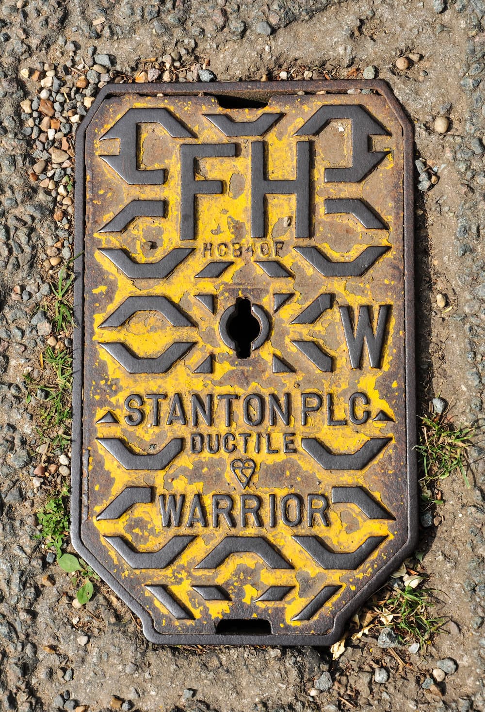 A metal fire hydrant cover with 'FH' on it.