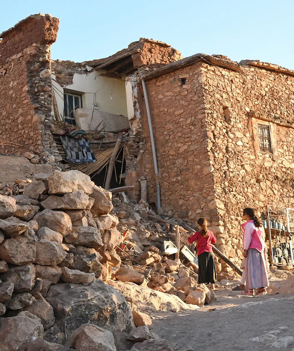 A damaged building in Morocco with two locals surveying the damage