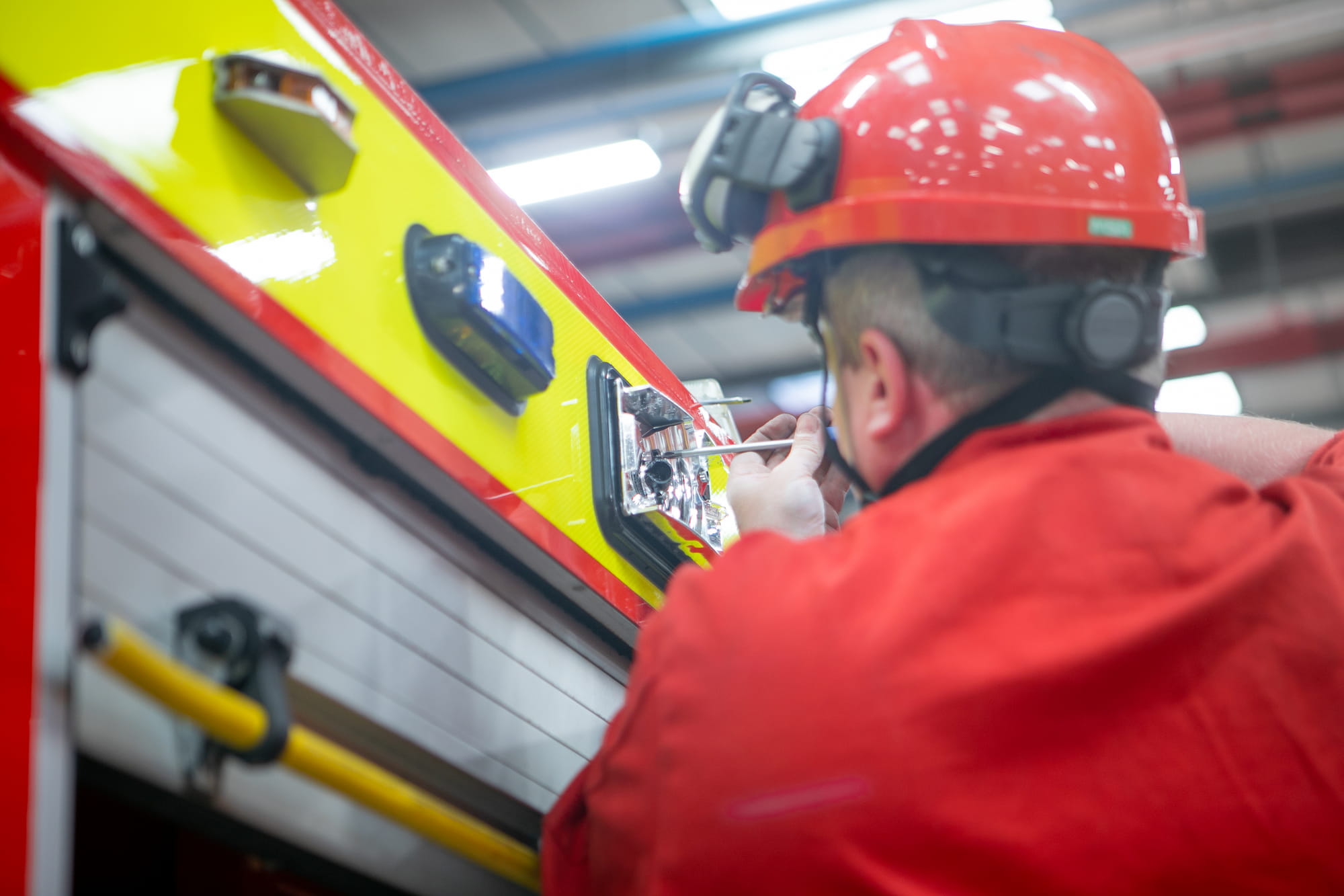 A workshops technician doing work on a fire engine light fixture