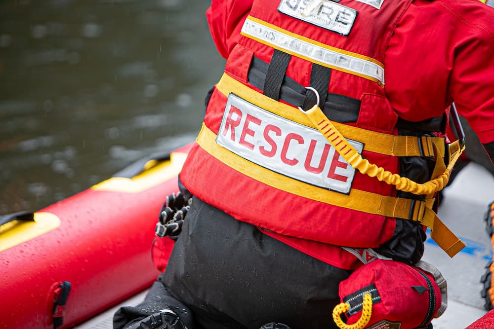 A close up of the word 'rescue' on the back of a firefighter wearing water rescue kit in a boat