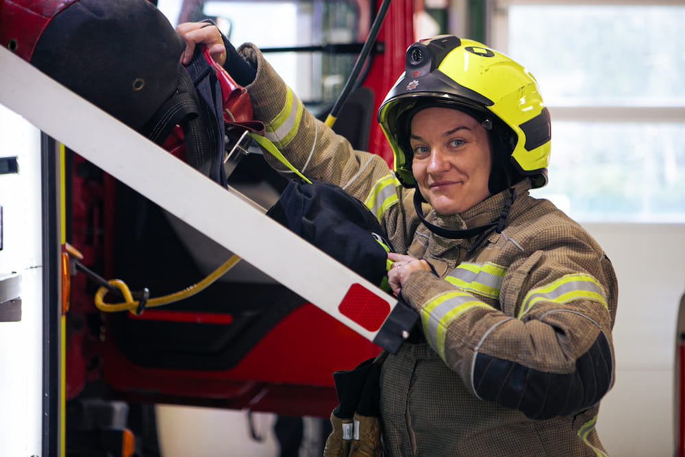 A female firefighter packing equipment on to a fire engine.