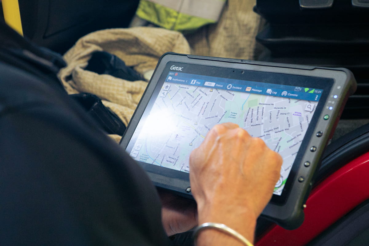 A hand pressing on a tablet used on a fire engine for information and navigation.